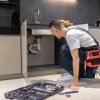 Male plumber looking under sink in kitchen